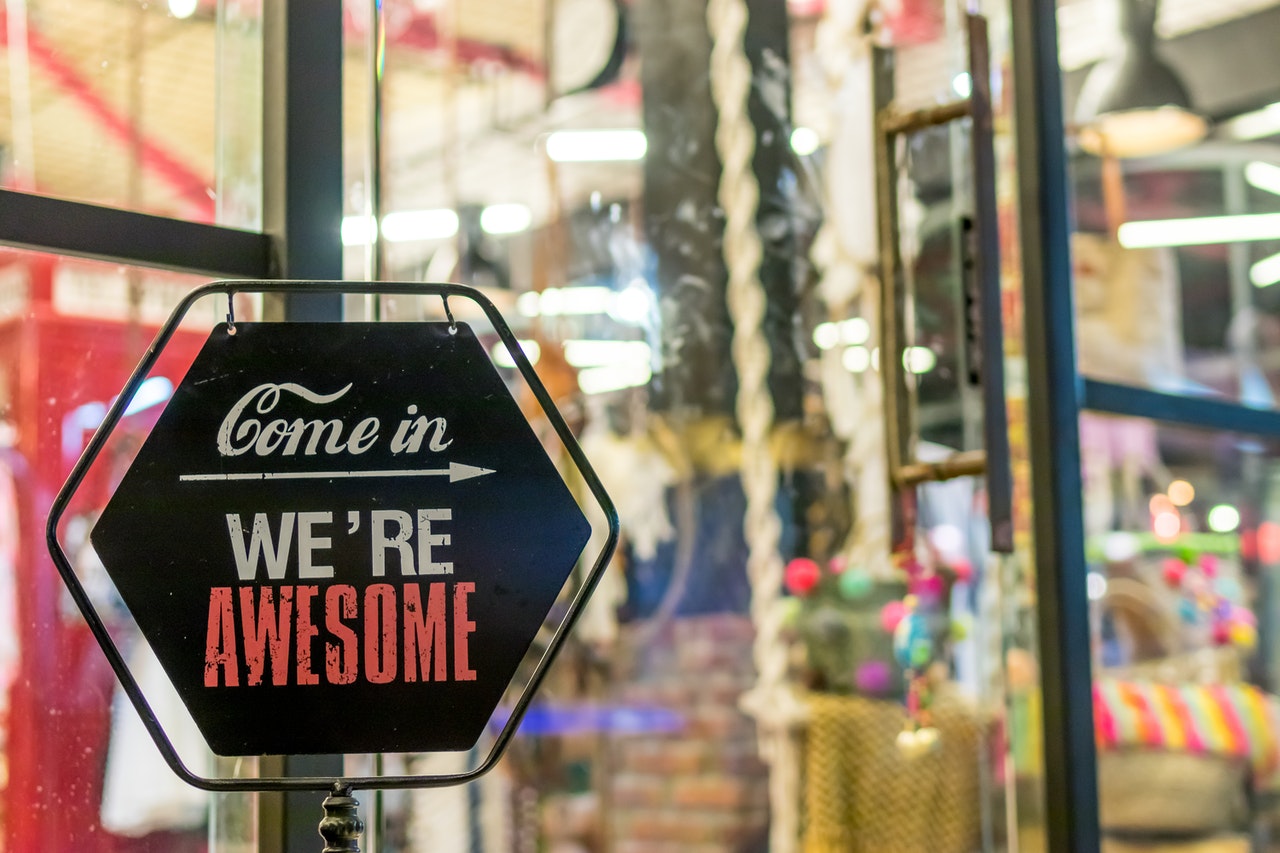 A hanging shop sign reading Come in, we're awesome
